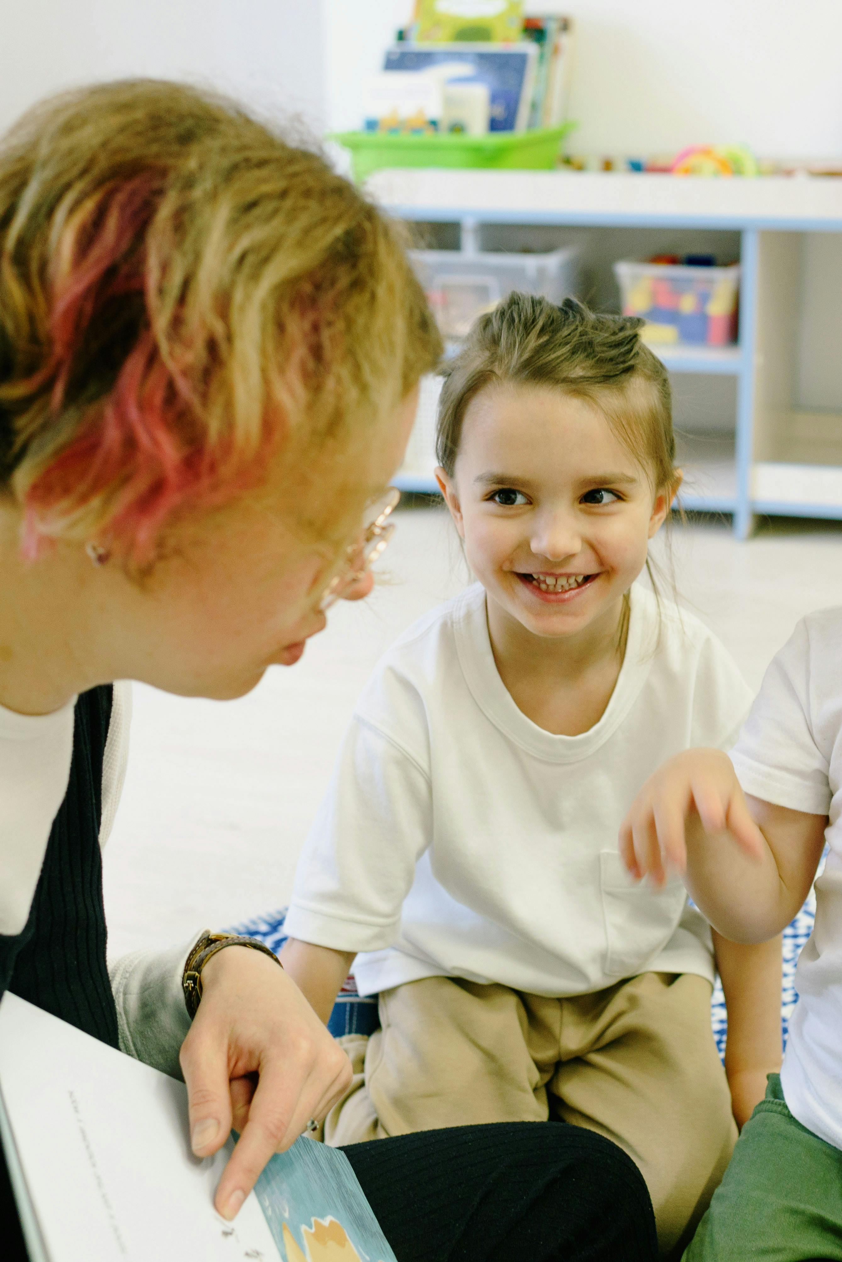 Erzieherin mit Kindern beim Bilderbuch zeigen
